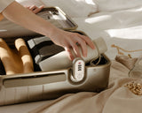 A hand placing a kiyo uvc water bottle inside the open interior of a hybrid carry-on in champagne, highlighting its organized packing space and built-in TSA-accepted lock.