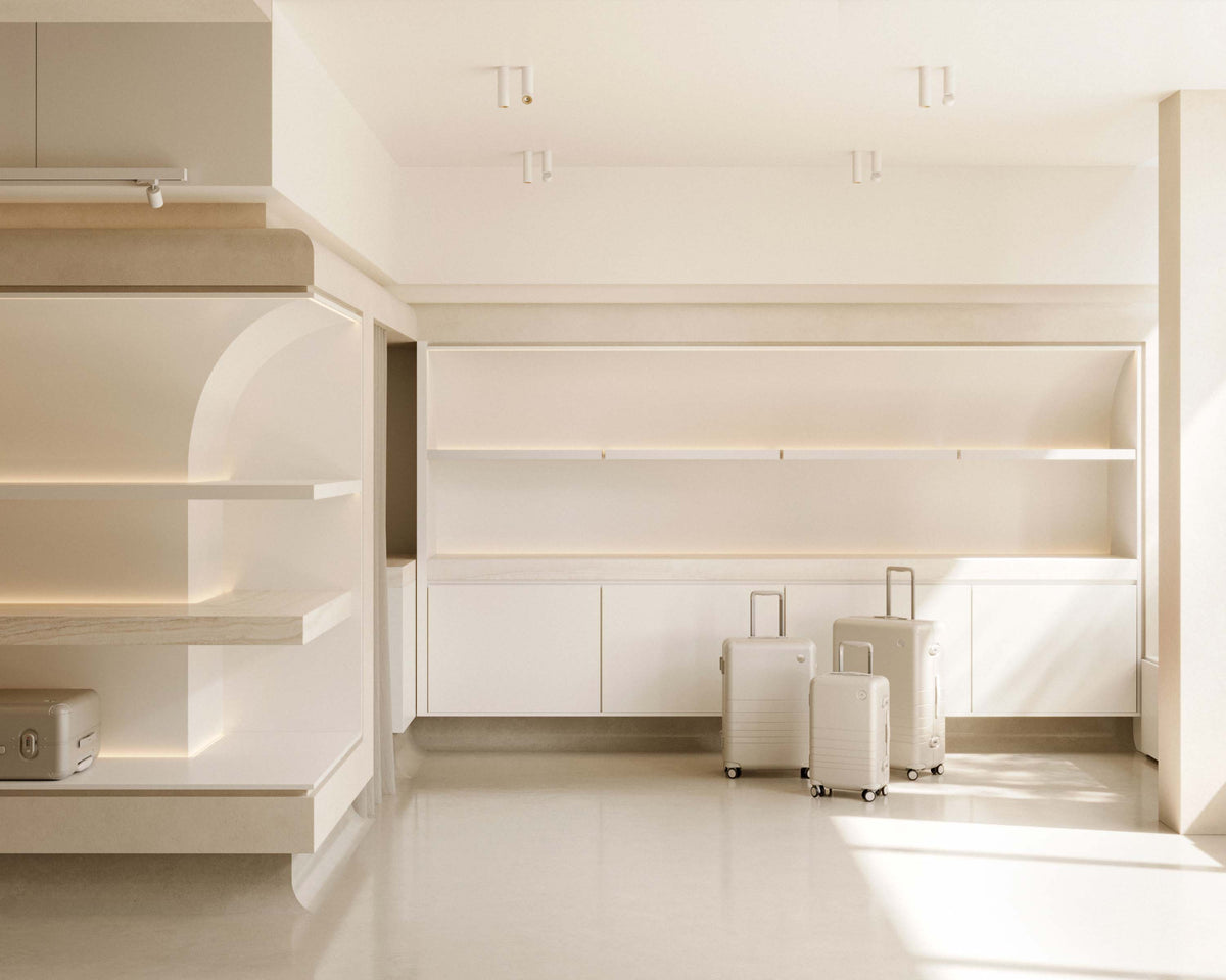 A modern retail interior with beige tones and natural light, displaying neatly arranged Hybrid suitcases in front of large white shelving units.