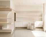 A modern retail interior with beige tones and natural light, displaying neatly arranged Hybrid suitcases in front of large white shelving units.