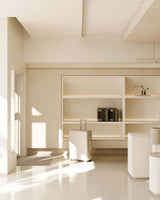 A bright, spacious showroom with Hybrid check-in luggage positioned in the foreground. Shelving on the wall holds two additional carry-on luggage, with soft light streaming in from large windows.