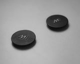 Two circular black logo pieces, embossed with the 