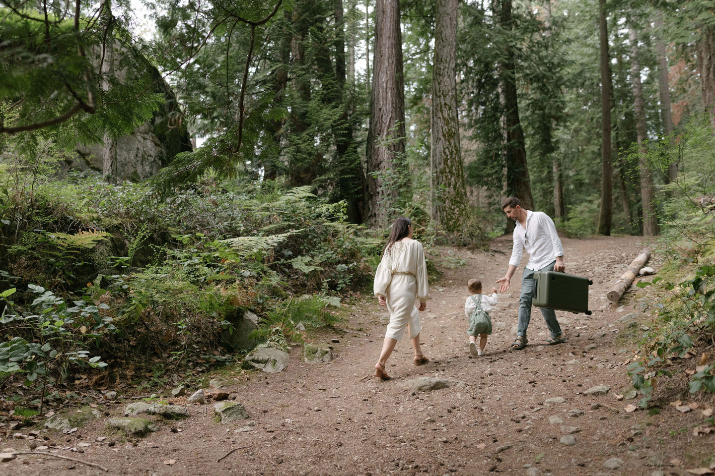 A family walking in the forest holding a Carry-On in Olive Green