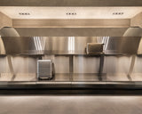 Display wall inside the Monos Georgetown store featuring aluminum luggage showcased against brushed steel shelving and soft ambient lighting.
