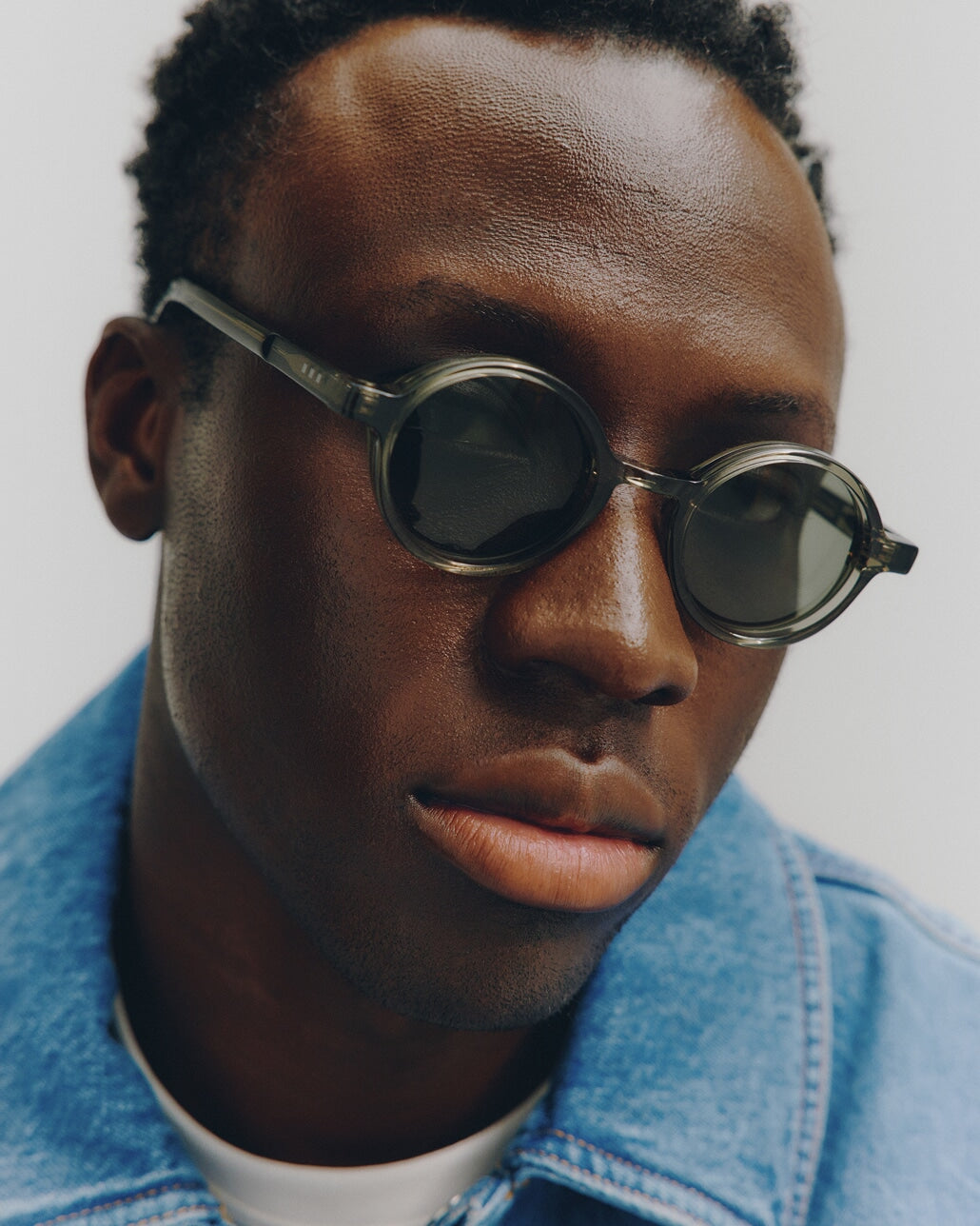 A man wearing the Cairn Sunglasses in Crystal Sencha / Grey Green Lens