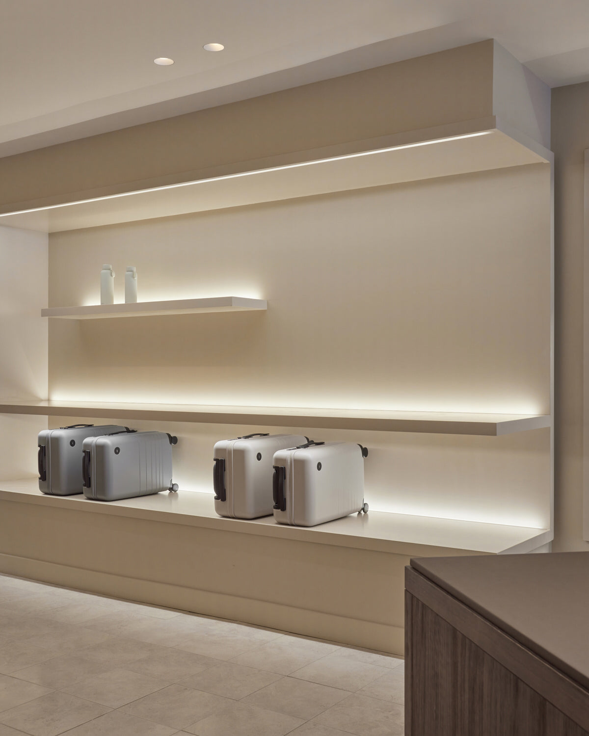 Monos Classic Collection luggage displayed on illuminated shelving inside the Boston store.