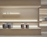 Monos Classic Collection luggage displayed on illuminated shelving inside the Boston store.