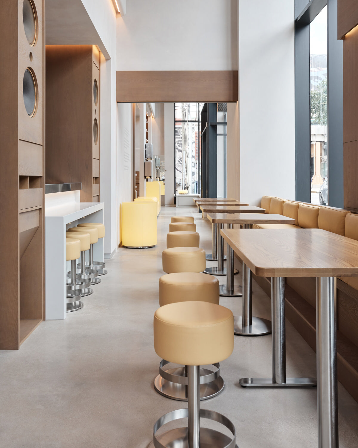 Modern restaurant interior with tables, stools, and a large window.